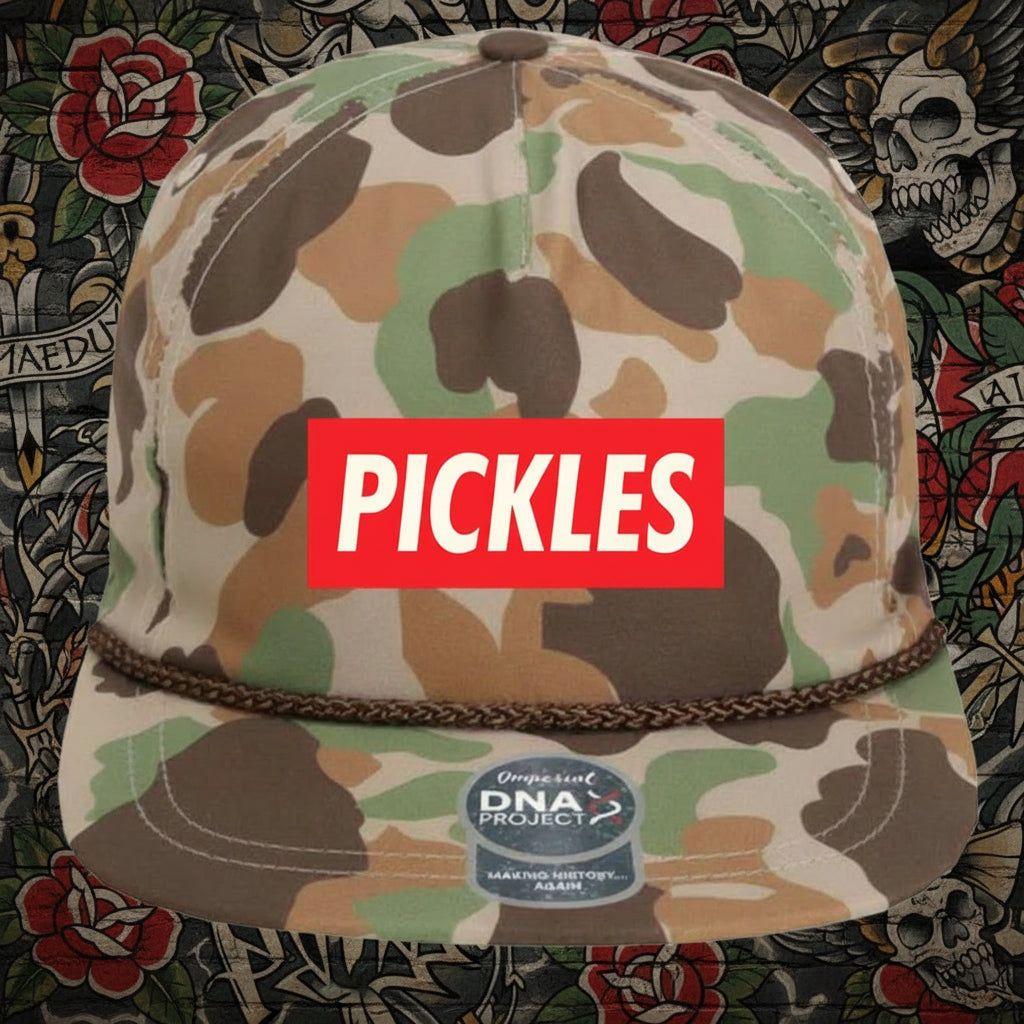 A camouflage flat-brim cap with a red rectangular front patch reading 'PICKLES' in white letters
